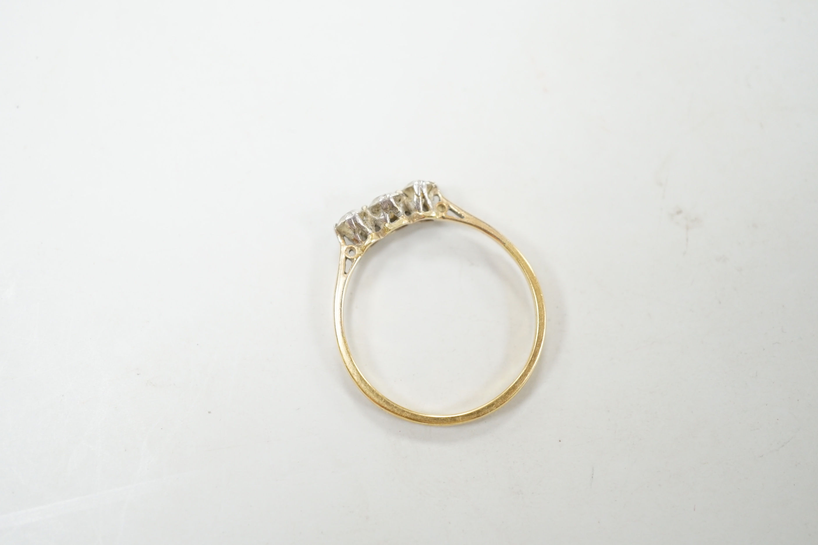 A yellow metal and three stone diamond set ring, size S/T, gross weight 2.1 grams.